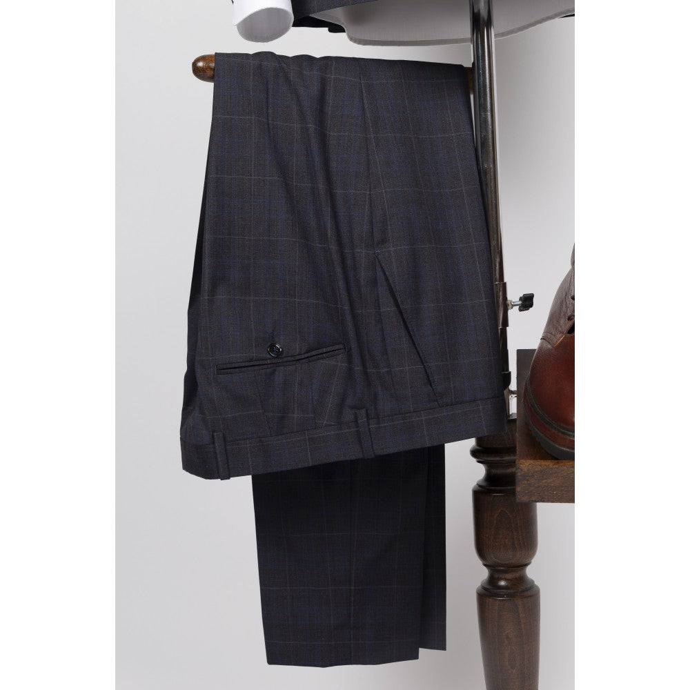 Suit trousers in navy wool with a tan windowpane check, folded over a valet stand, showing the slanted side pocket and waistband.