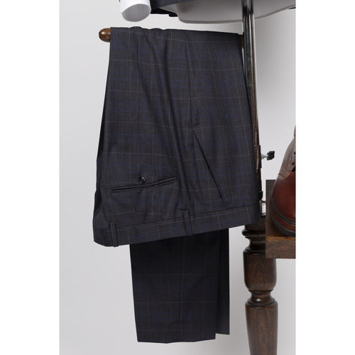Suit trousers in navy wool with a tan windowpane check, folded over a valet stand, showing the slanted side pocket and waistband.