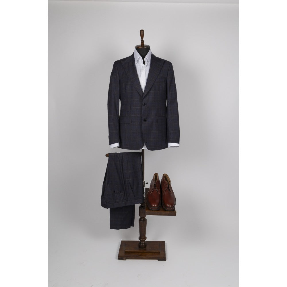 Navy blue windowpane check wool suit displayed on a wooden valet stand with a white shirt and brown leather shoes.