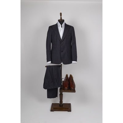 Navy blue windowpane check wool suit displayed on a wooden valet stand with a white shirt and brown leather shoes.